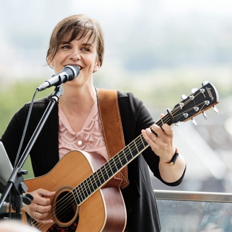 Kate mit Gitarre und wachem, freundlichen Blick 